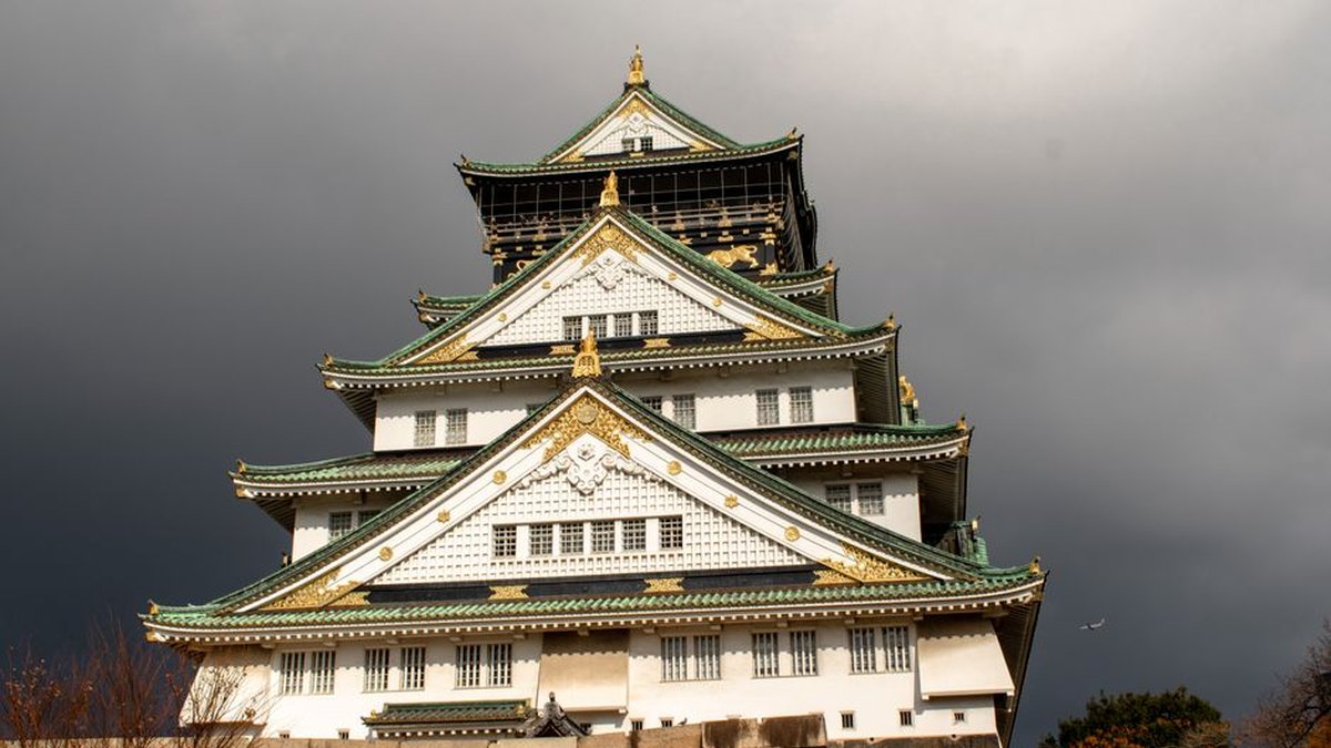 Stunning view of Osaka Castle with dramatic dark clouds. Iconic Japanese landmark.
