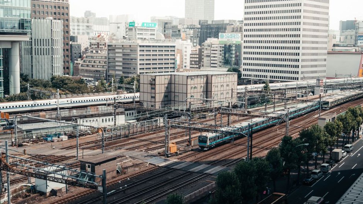 A bustling train station in Tokyo with city skyscrapers in the background.