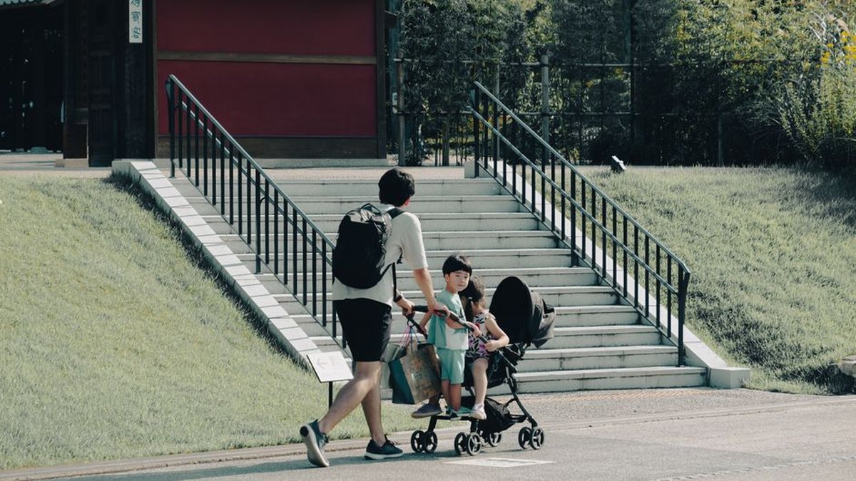 A father pushes a stroller with children on a sunny day in Nagoya, Japan. Outdoor fun and leisure activities.