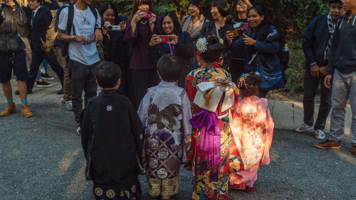 A vibrant gathering in Shibuya, Tokyo featuring children in traditional kimonos surrounded by tourists.
