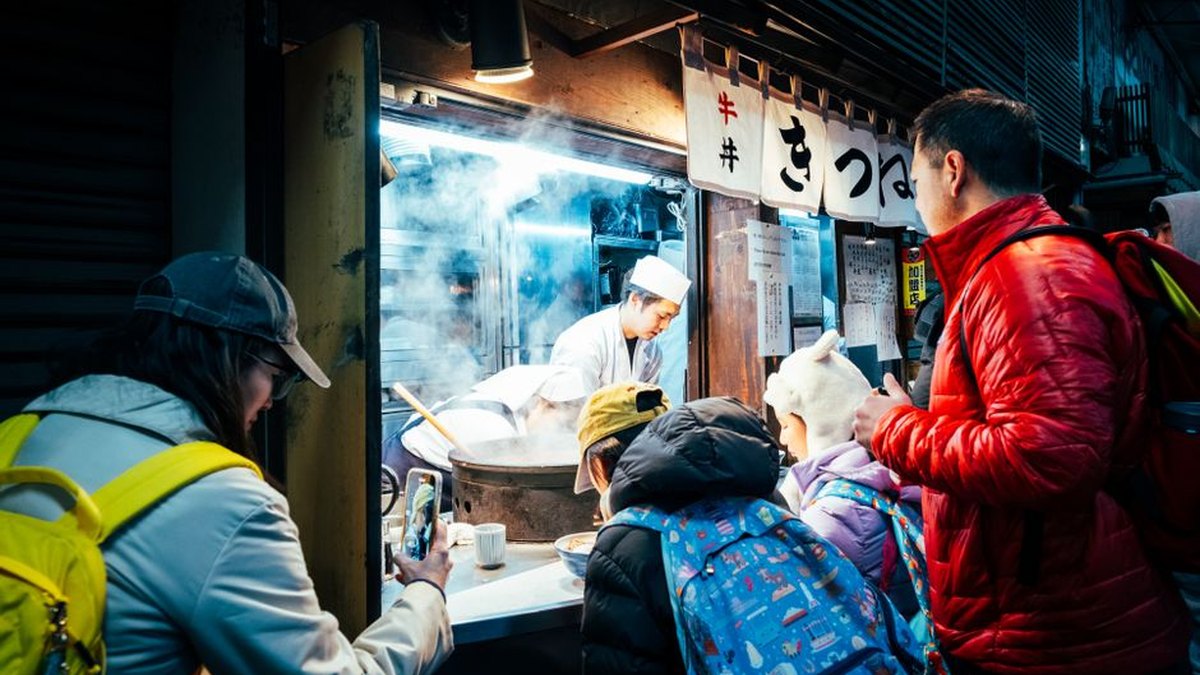 A bustling street food stall in Tokyo, Japan, attracts a crowd at night with delicious offerings.