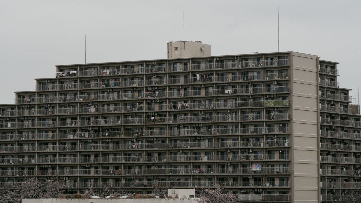 A high-rise apartment building in Tokyo with cherry blossoms in front