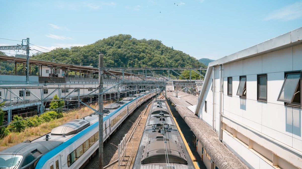 Overhead view of a bustling train station in Hachiōji, Tokyo during a sunny day.