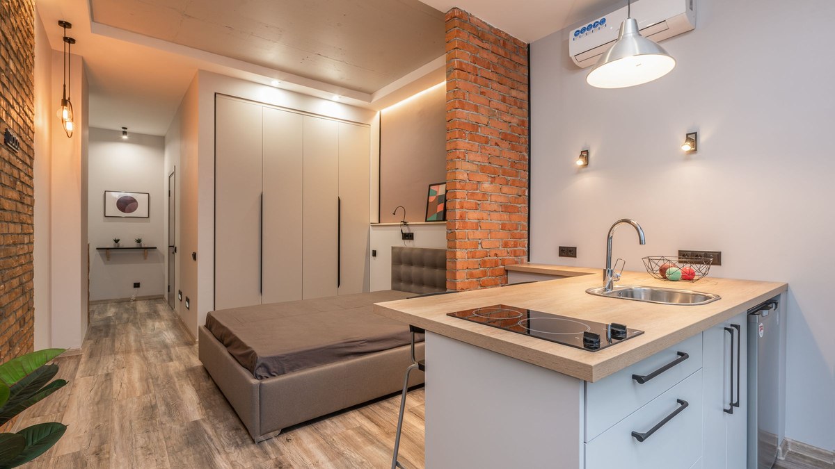 A compact apartment kitchen with a cooktop, fridge and worktop